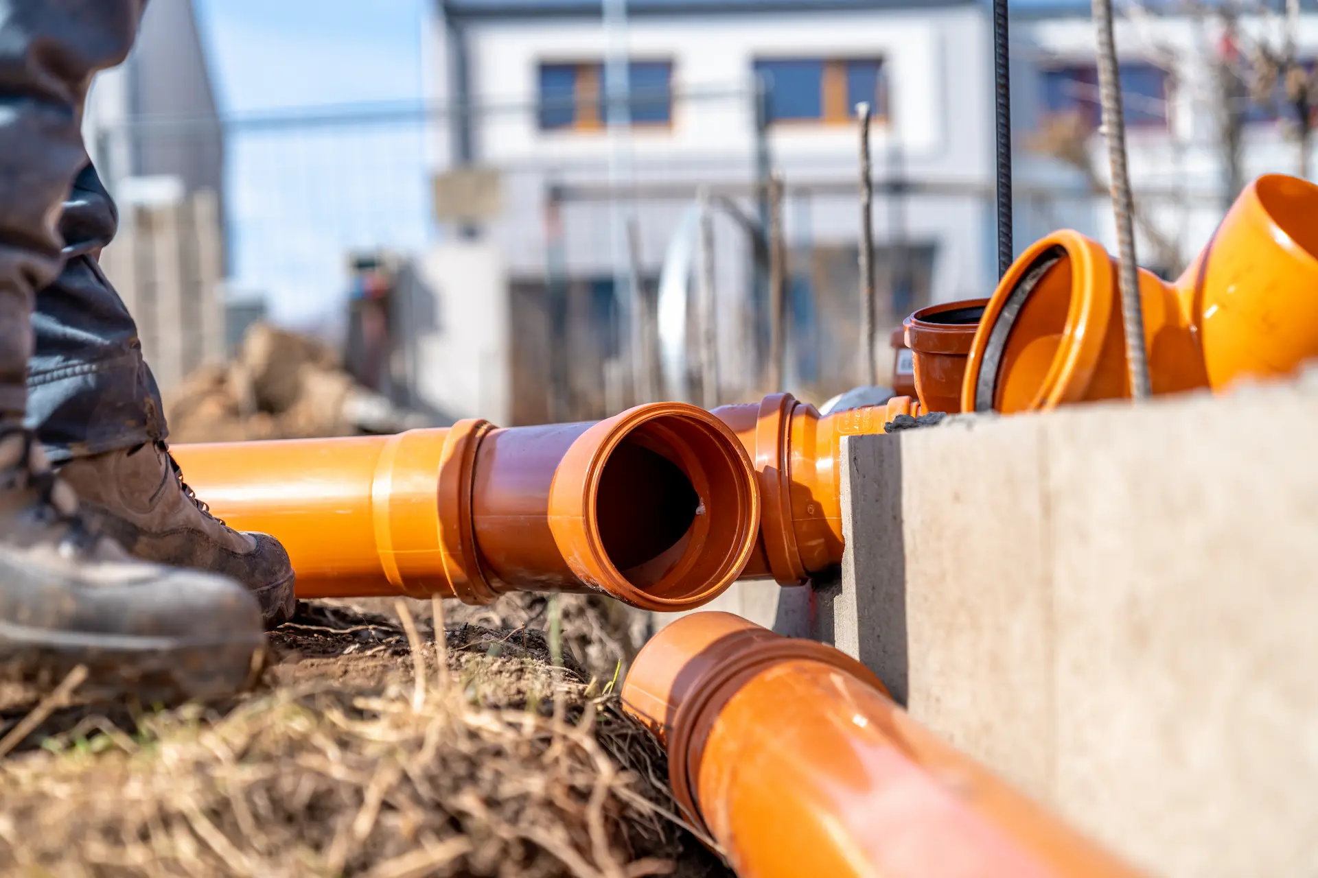 man's boots by orange disconnected pipes